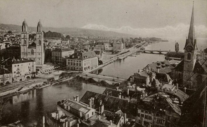 Melnbalta pastkarte, kurā redzama Cīrihes ainava. Pa vidu redzama upe, upes krastos - daudz ēku, katrā pusē arī pa vienai baznīcai ar augstiem torņiem. Pāri upei divi tilti.