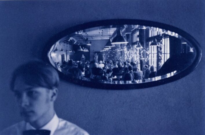 Zilibaltā fotogrāfijā redzams spogulis, kurā atspīd "Andalūzijas Suņa" kafejnīcas telpas, kur notiek Prozas lasījumi.